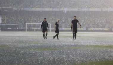 Referees inspect the field as it rains prior to a match